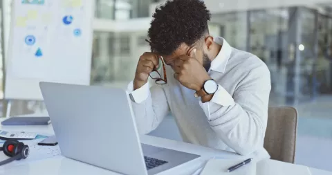 Personne qui à la tête dans ses mains devant son ordinateur